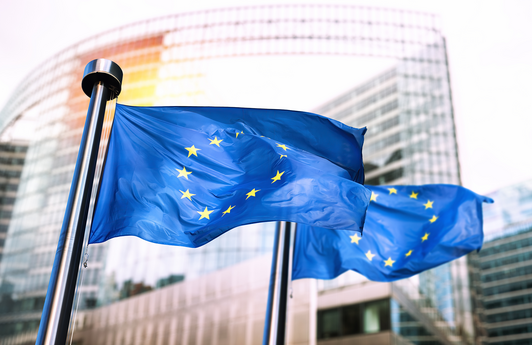 Zwei wehende Europa-Flaggen vor einem Gebäude.