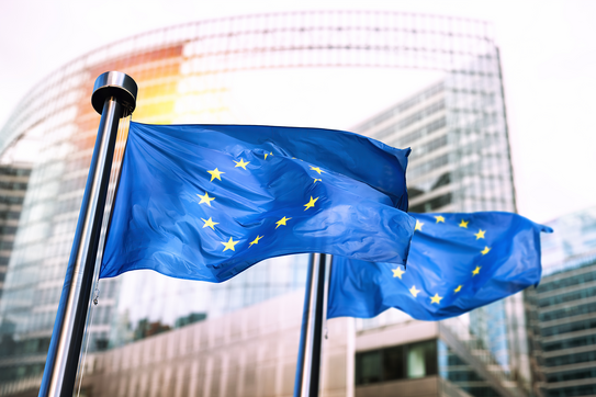 Zwei wehende Europa-Flaggen vor einem Gebäude.