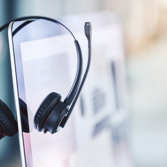 Ein Headset hängt seitlich auf einem Desktopbildschirm