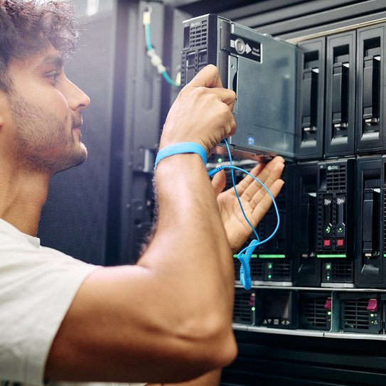 Techniker schließt ein Netzwerkkabel an einem Serverrack in einem Rechenzentrum an.