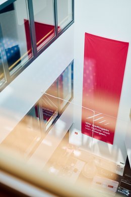 Ein Blick von unserem Lichtflur in den Innenhif, an der Wand hängt ein rotes Banner mit unserer Vision