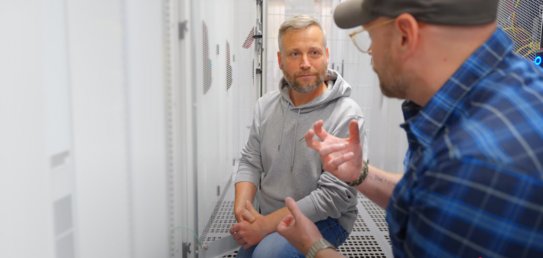 Zwei Personen im Gespräch zwischen Serverracks in einem hochsicheren IT-Bereich