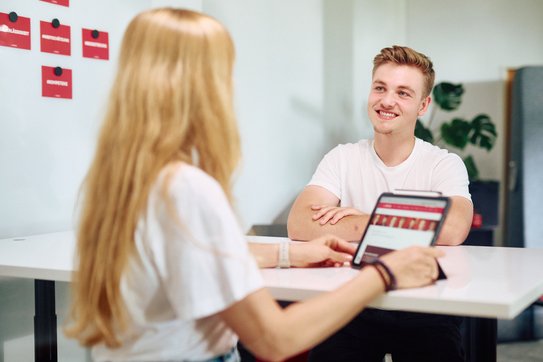 Eine Frau unterhält sich mit einem jungen Mann in einem modernen Besprechungsraum