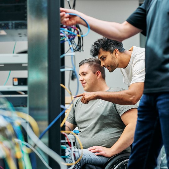 Mitarbeitende schauen gemeinsam in einen Serverturm
