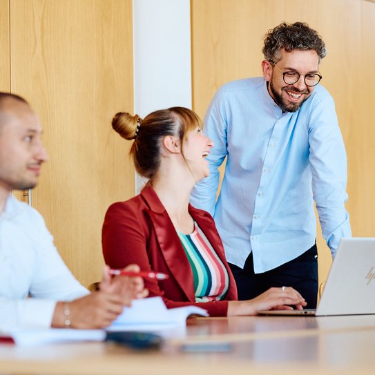 Eine Person erklärt anderen in einer Schulungssituation Inhalte an einem Laptop