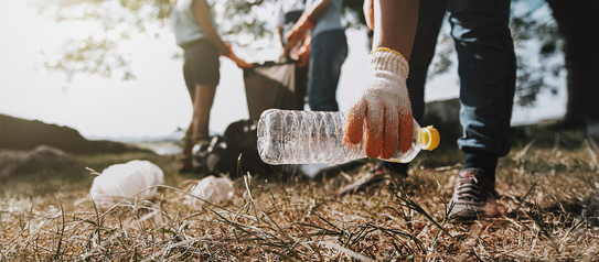 Eine Person greift auf dem Boden nach einer Plastikflasche